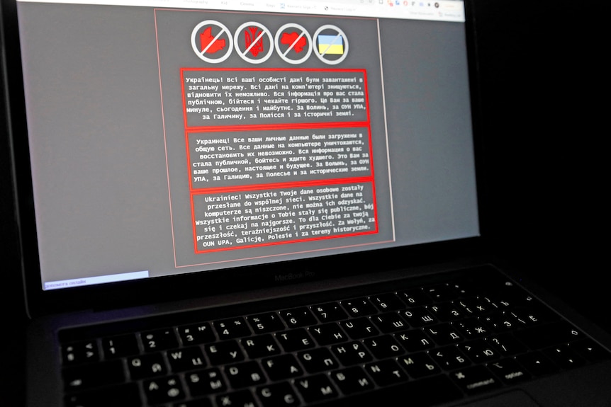 A laptop screen displays a warning message in Ukrainian, Russian and Polish