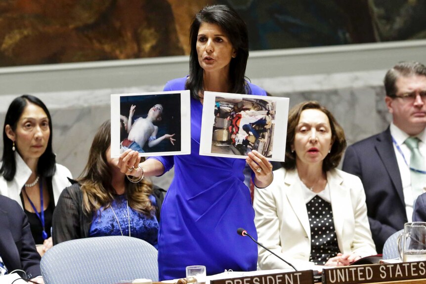 US ambassador to the UN Nikki Haley holds up pictures of victims of a chemical attack in Syria during a UN meeting.