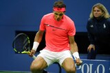 Rafael Nadal crouches and clenches his fists in celebration of winning a point.