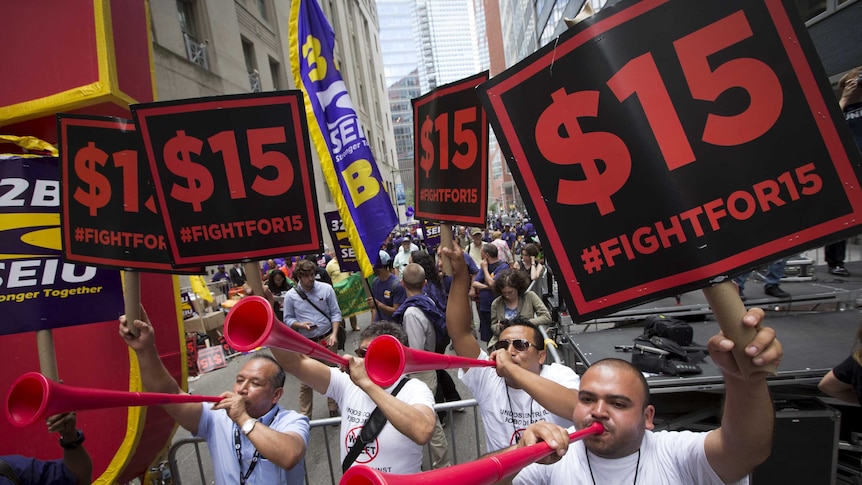 People celebrate the passage of the minimum wage for fast-food workers by the New York State Fast Food Wage Board during a rally in New York