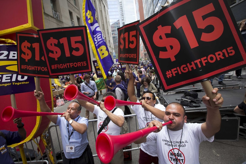 People celebrate the passage of the minimum wage for fast-food workers by the New York State Fast Food Wage Board during a rally in New York