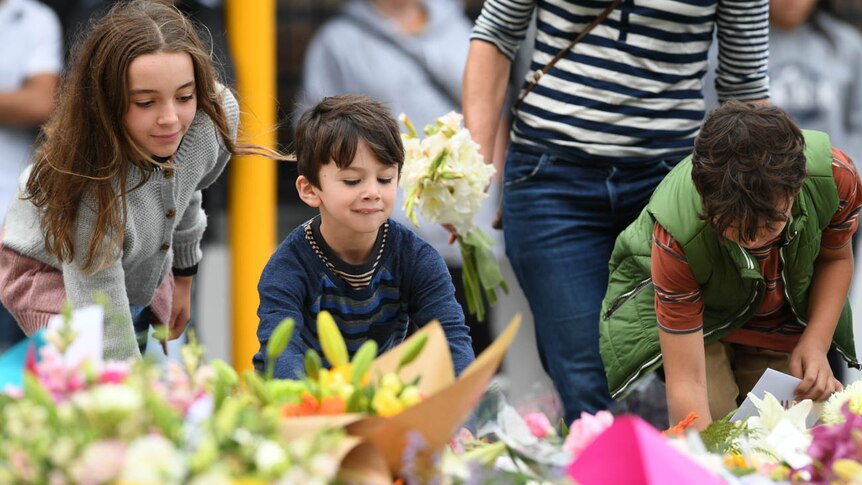 Children lay flowers at a memorial on Dean's Avenue in Christchurch.