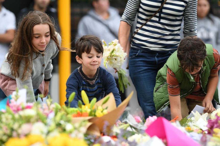 Children lay flowers at a memorial on Dean's Avenue in Christchurch.