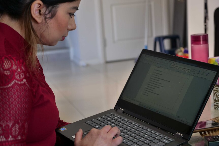 A young woman of Indian background operates a laptop.