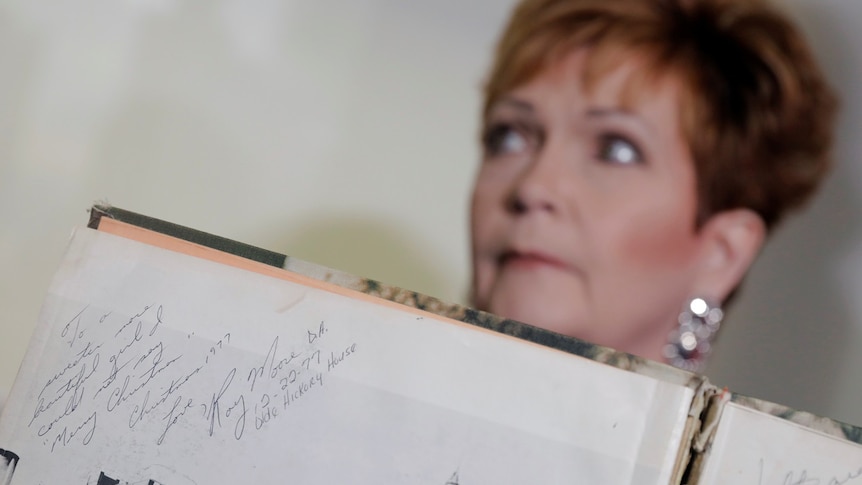 Beverley Young Nelson who has accused Sen Roy Moore of sexual abuse holds up a school year book showing Mr Moore's signature.