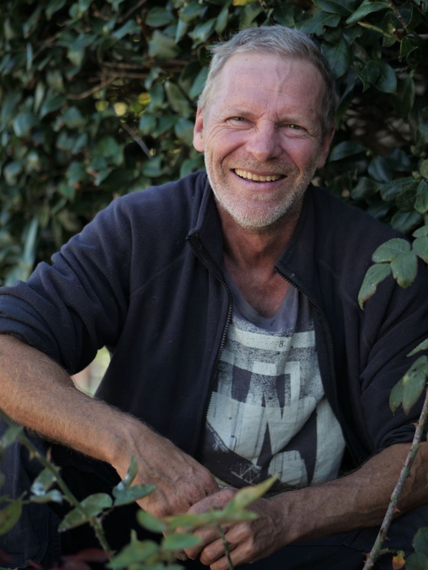 A man in front of a bush