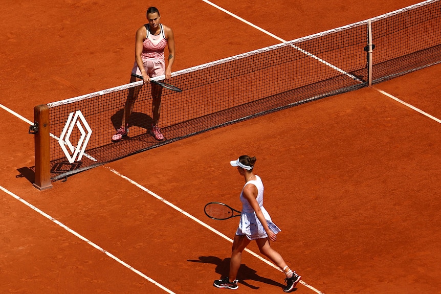 Aryna Sabalenka waits at the net after winning her quarter final match as Ukraine's Elina Svitolina walks past