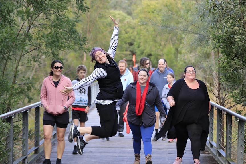 A woman jumps for the camera as three other women walk.