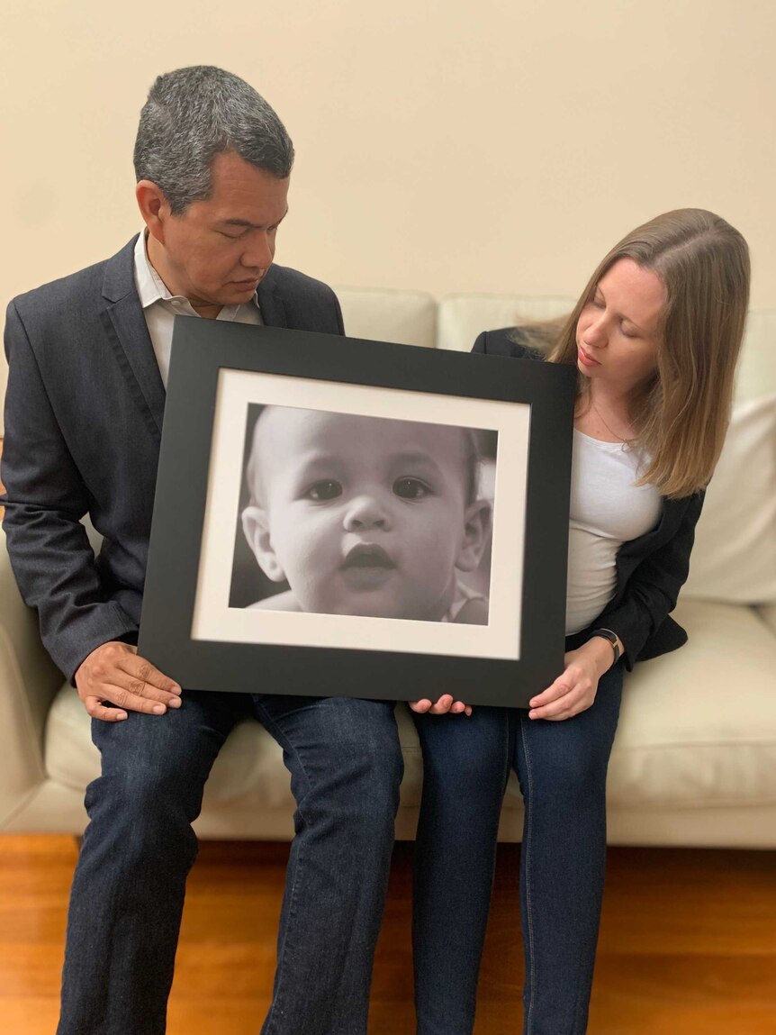 Craig Oehlers and Sarah Copland hold a photo of their son Isaac Oehlers.