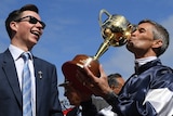 Young trainer laughs as Jokey kisses Melbourne Cup trophy