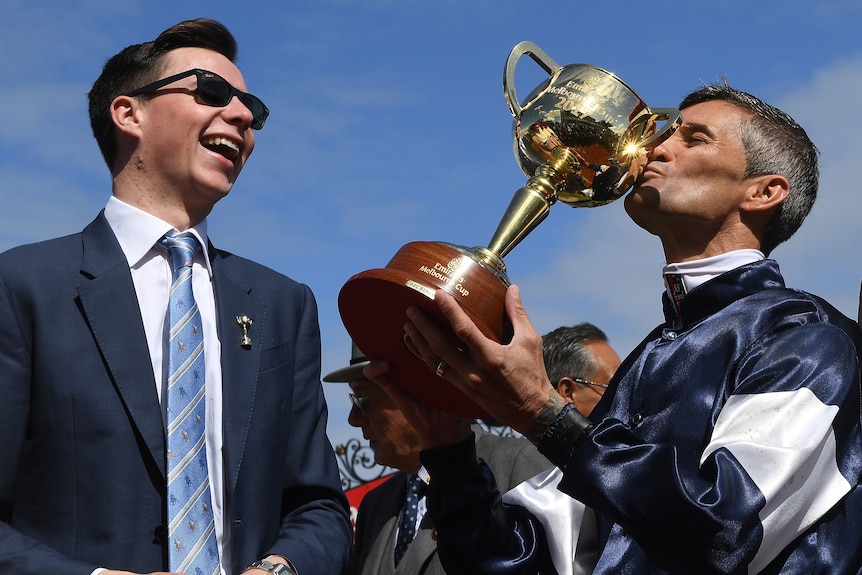 Young trainer laughs as Jokey kisses Melbourne Cup trophy