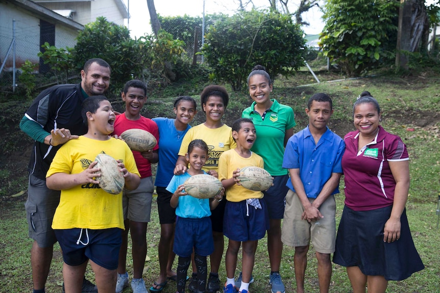 Children from Suva's Hilton Special School excitedly pose for a portrait with teachers and NRL instructor, Lana.