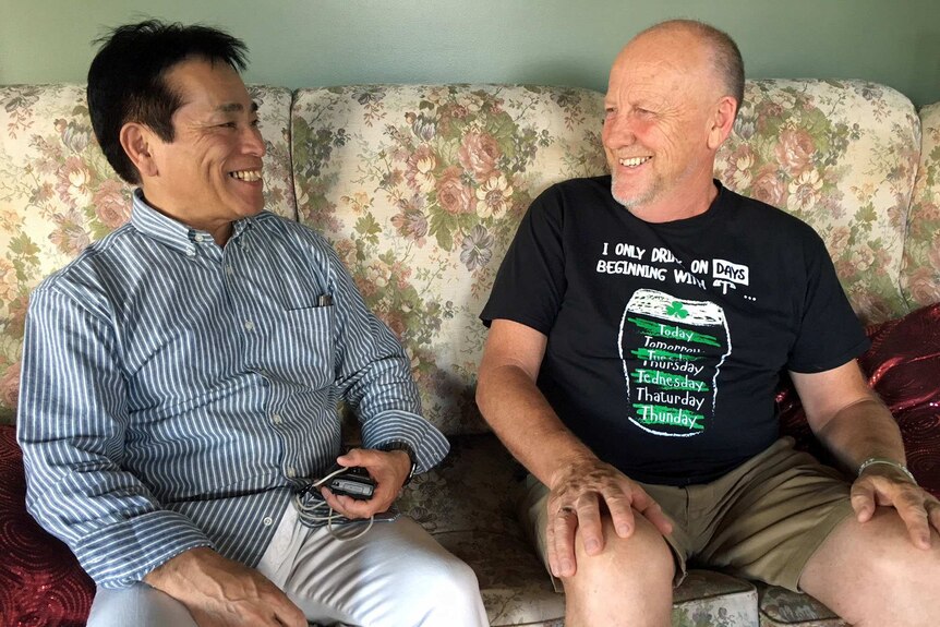 Fuji Maruyama and David Hall sit on a couch together.