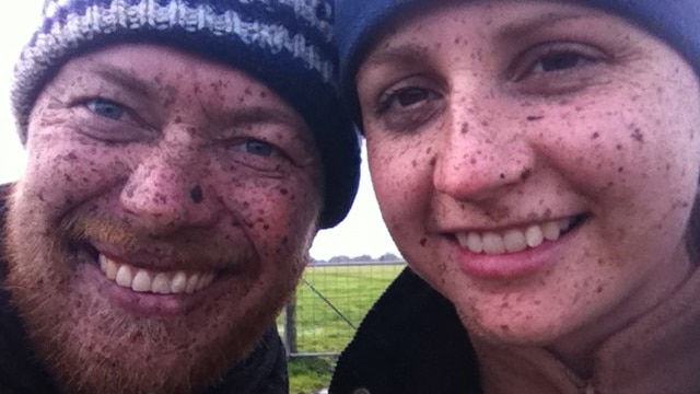 Couple smiling with mud splatters.