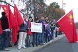 Pro-China demonstrators with flags and signs line-up on side of Canberra road