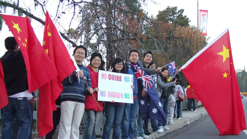 Pro-China demonstrators with flags and signs line-up on side of Canberra road