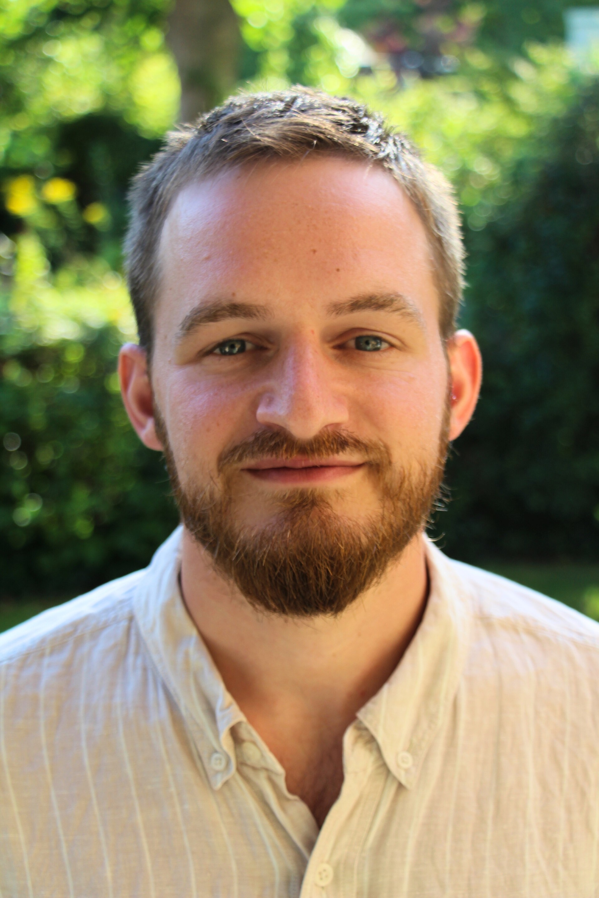 Un primer plano de un hombre mirando a la cámara. Un fondo natural verde se desdibujó detrás de él.