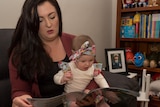 Hayley Boswell sits her daughter Evie on her lap and reads her book to her.