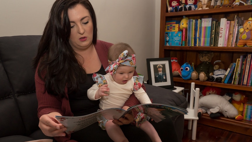 Hayley Boswell sits her daughter Evie on her lap and reads her book to her.