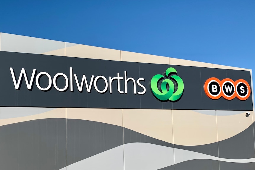 The outside of a Woolworths and BWS is a wall with signs naming the business.