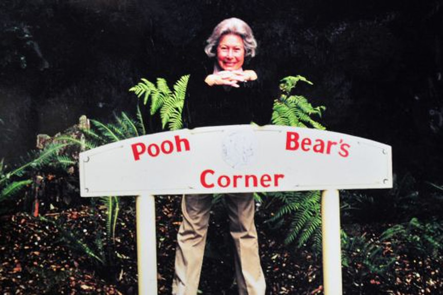 Lady pictured in an older photo with a sign saying 'Pooh Bear's Corner'