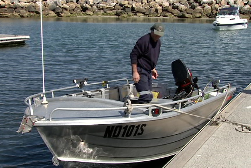 A man on a boat tied to a concrete dock