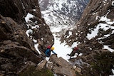 Skiers climbing over rocks