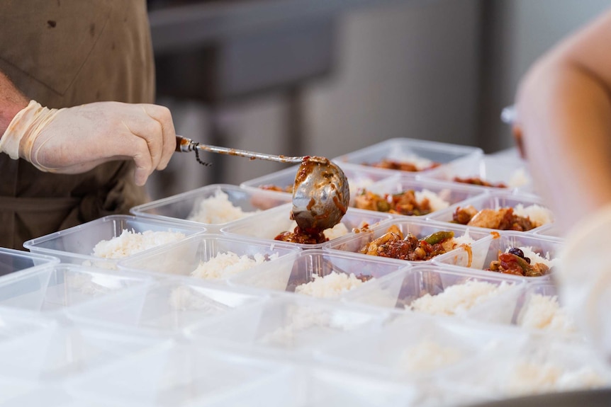 Arm serving out food into takeaway containers