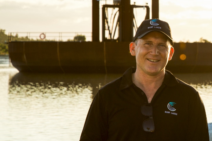 the founder of the company standing in front of his wave pool wearing a branded polo and hat