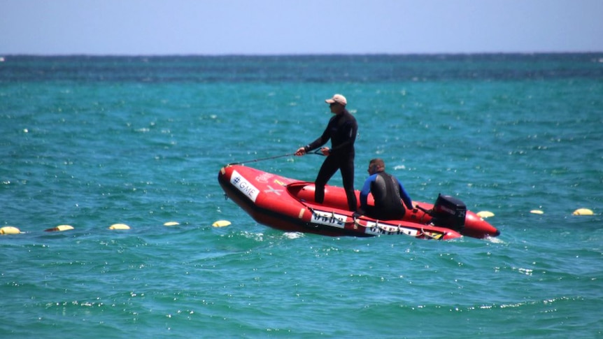 Two men wearing wetsuits in a rubber dinghy on the ocean.