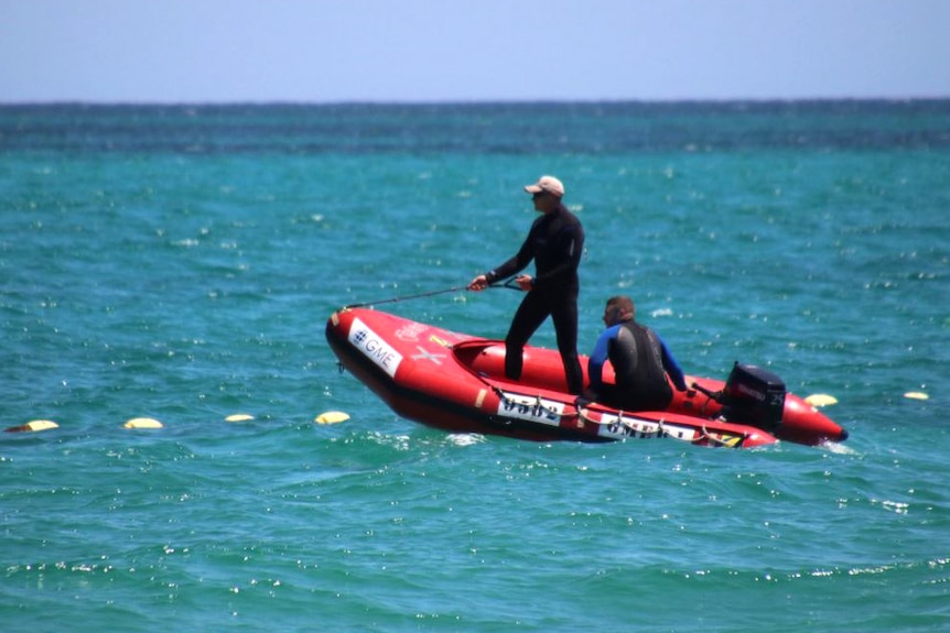 Two men wearing wetsuits in a rubber dinghy on the ocean.