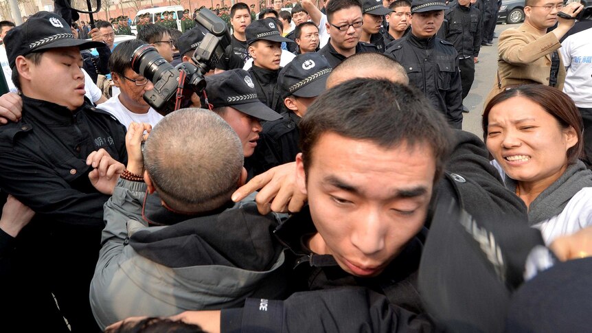 Grieving Chinese relatives of passengers on missing flight MH370 try to remove a police barricade.