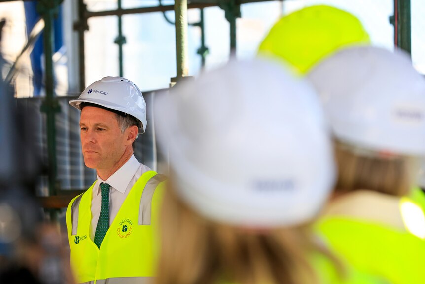 a man wearing a hard hat inside a construction site talking to other people wearing hard hats