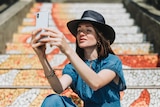 Girl with freckles wearing hat takes a selfie
