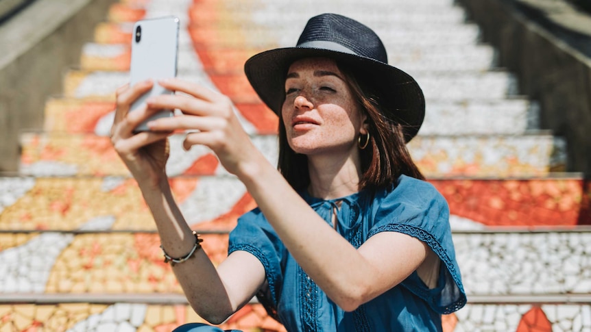 Girl with freckles wearing hat takes a selfie