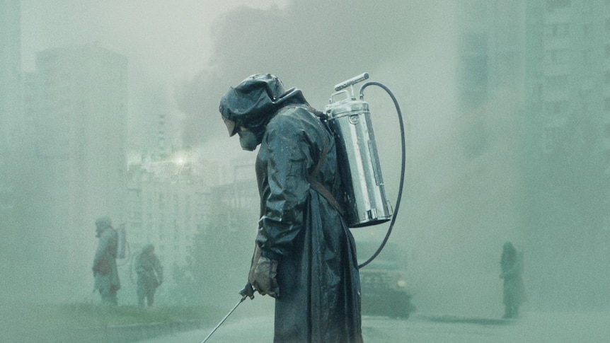 A person wearing a protective suit spraying the ground. The air is thick with smoke with a hint of a green tinge.
