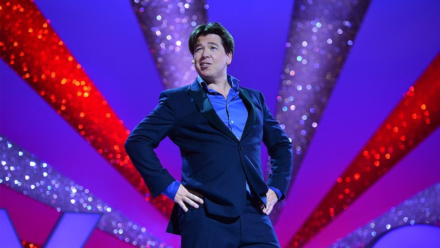 British comedian Michael McIntyre with hands on hips during a show.