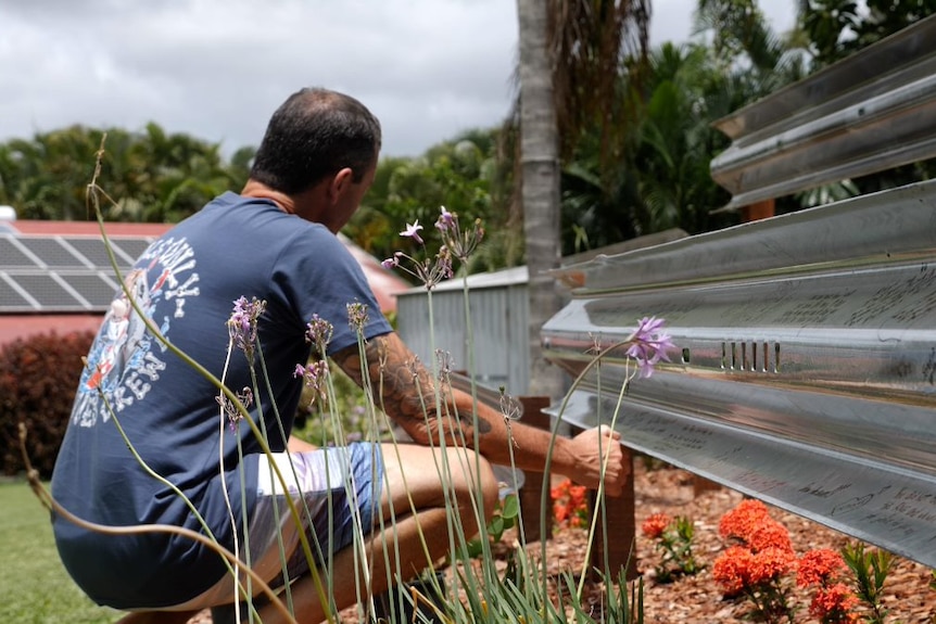 Shane Yore kneels at the memorial garden at the family home in Yeppoon.