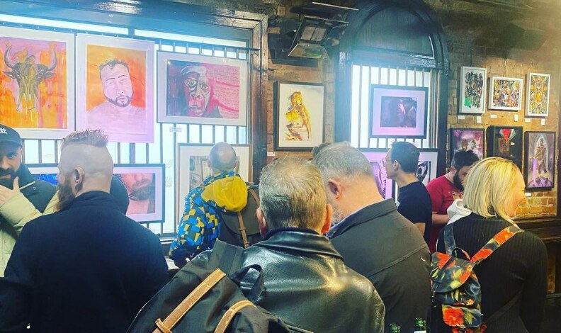 Men stand in a pub surrounded by art work.