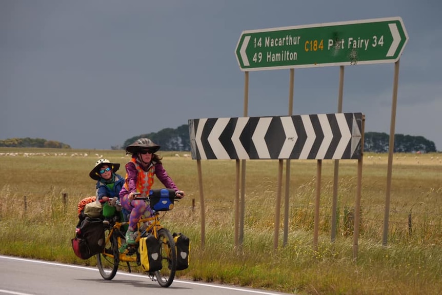 Wilfred and Nicola Hughes ride their tandem bicycle past a road sign pointing to Port Fairy.