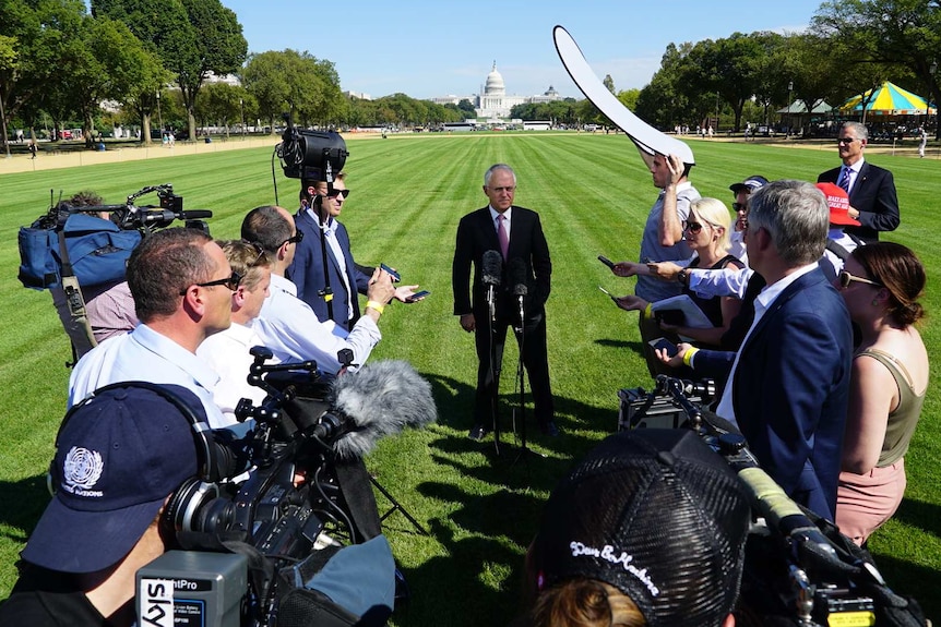 Wide shot media standing around Turnbull on lawn with Capitol Building in the background.