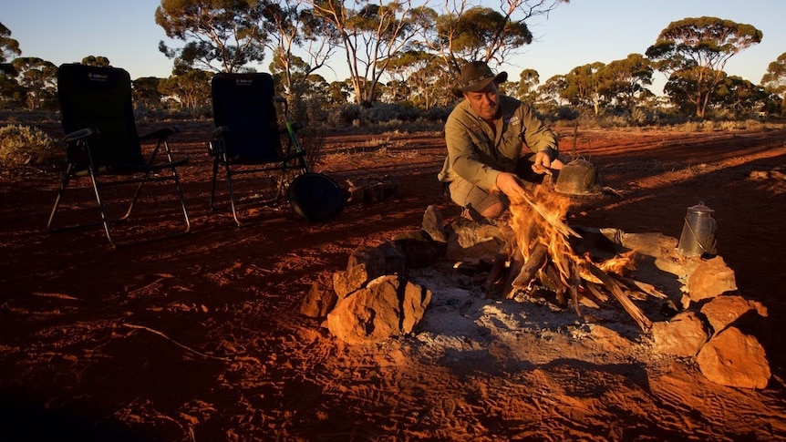 A gold prospector stokes a camp fire in the WA Goldfields.