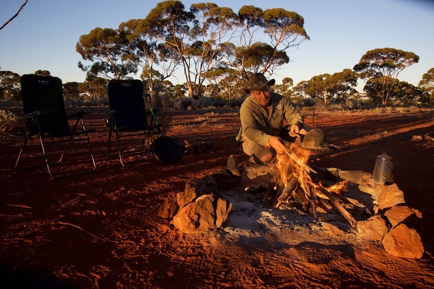 A gold prospector stokes a camp fire in the WA Goldfields.