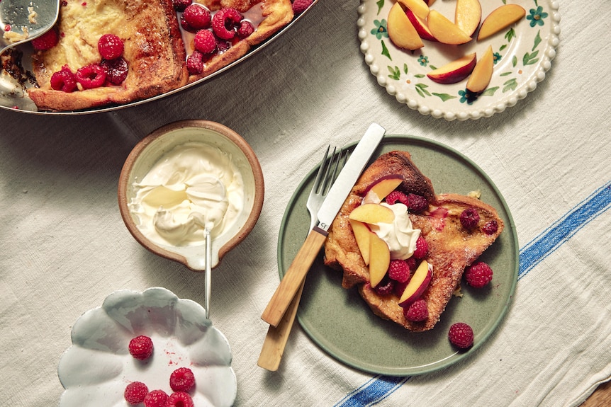 A slice of baked French toast is served with raspberries, maple syrup and mascarpone. An easy recipe for entertaining.