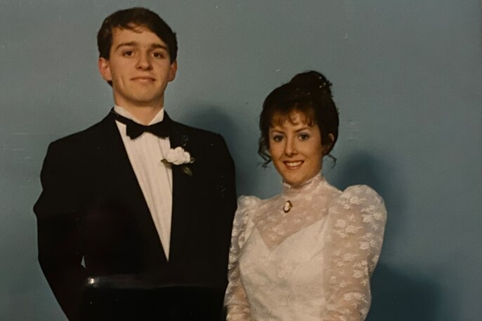 A young man and woman, both wearing formal deb ball attire, pose side-by-side.