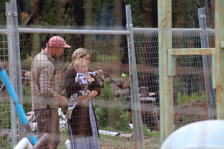 Family in front of fence around building site.