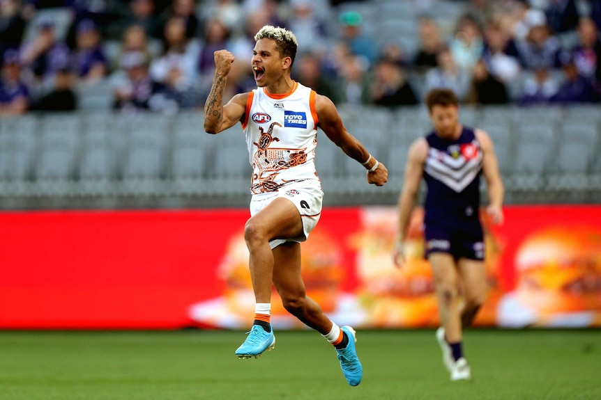 A GWS Giants player jumps in the air and pumps his fist as he celebrates a goal against the Dockers.