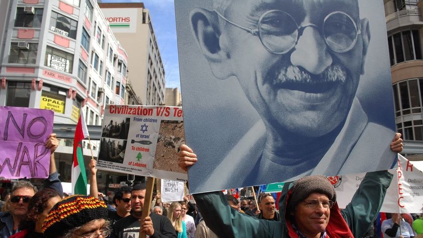 Man carries a placard depicting Mahatma Gandhi at a peace protest.