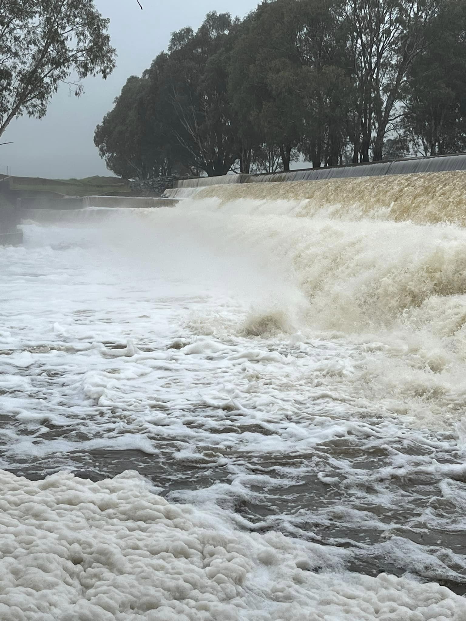 water rushes over a weir