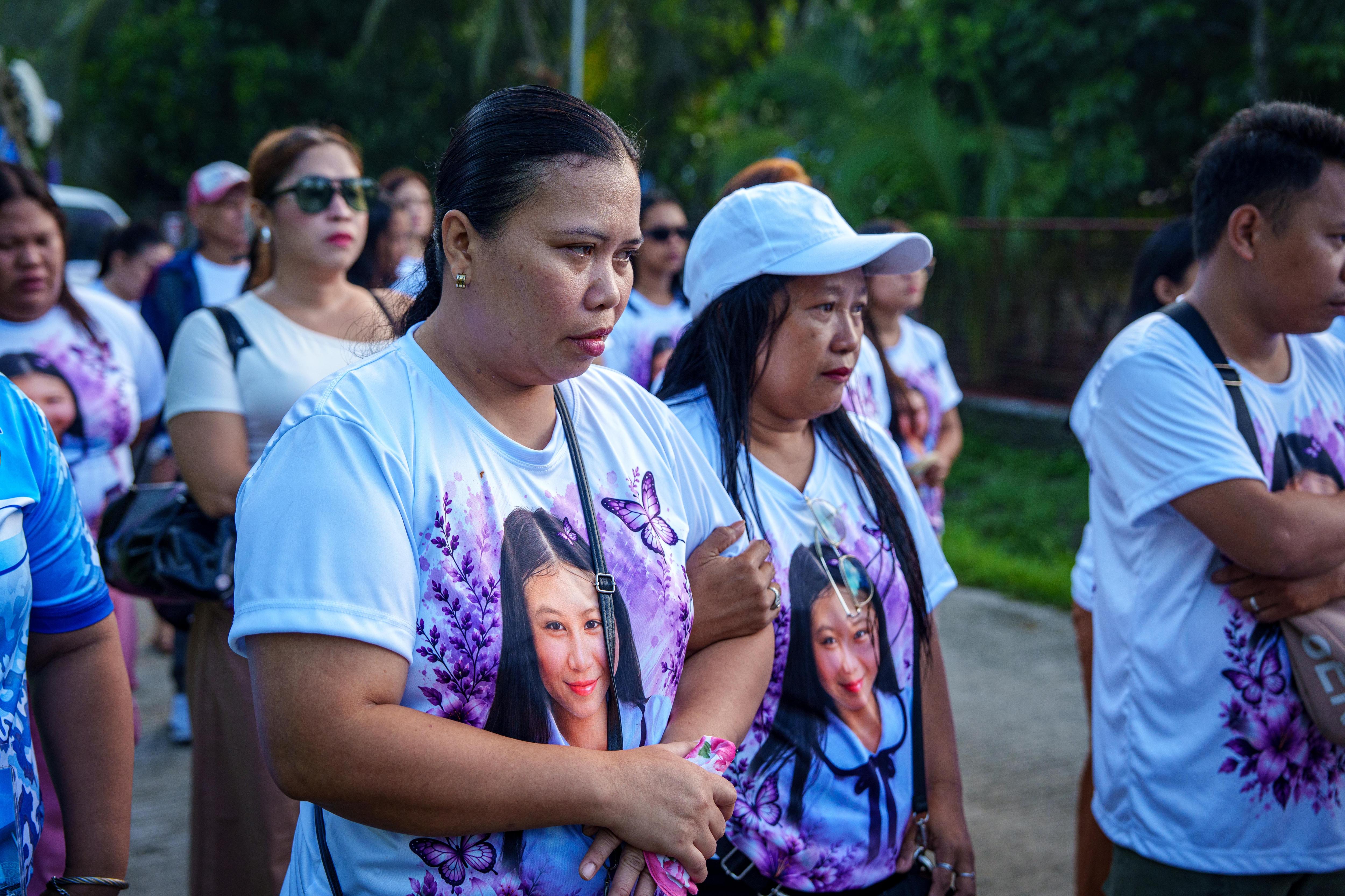 A middle-aged Filipino woman wearing a t-shirt with a young schoolgirl's face on it walks with a group of people.